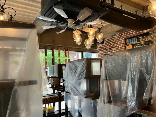 客席のカウンターやテーブルをビニールで養生し、洗浄水の飛散を防ぐ準備をした様子
