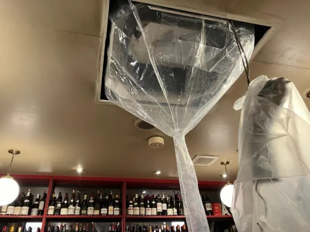天カセ室内機に洗浄カバーを取り付け、酒瓶棚の上で内部洗浄の準備をしている様子